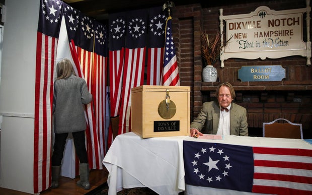 Dixville Notch resident Deborah Tillotson, left, enters a voting booth while her husband Tom Tillotson moderates the votes in Dixville Notch, New Hampshire, on Feb. 11, 2020.