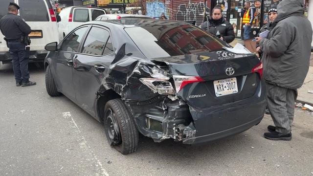 A black sedan with damage to the rear left tire and bumper. 