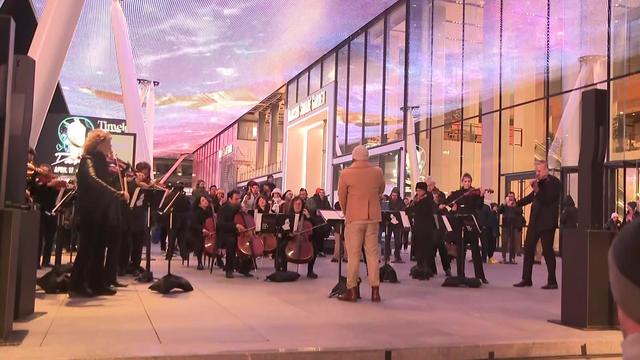 A live orchestra performs outside the entrance to Penn Station. 