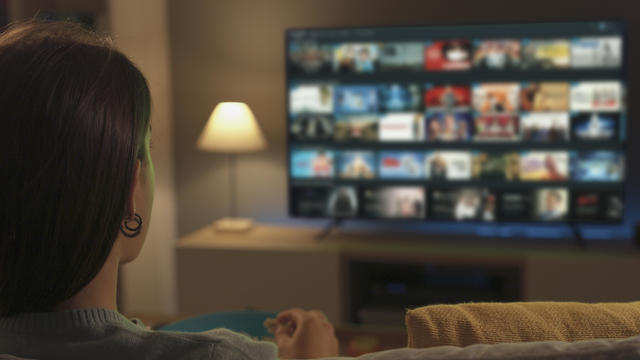 Young woman watching video on demand on her TV 