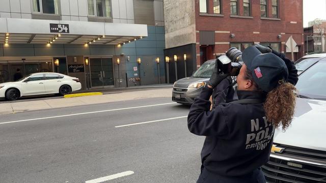 An NYPD officer takes a photo of the exterior of the SoHo 54 hotel. 