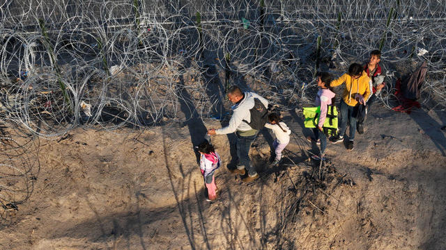 An aerial view shows migrants walking next to razor wire after crossing the Rio Grande to seek asylum at sunset in Eagle Pass, Texas, on Feb. 4, 2024. 