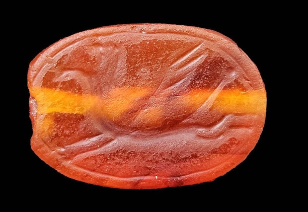 The winged creature carved on the back of a scarab-shaped amulet