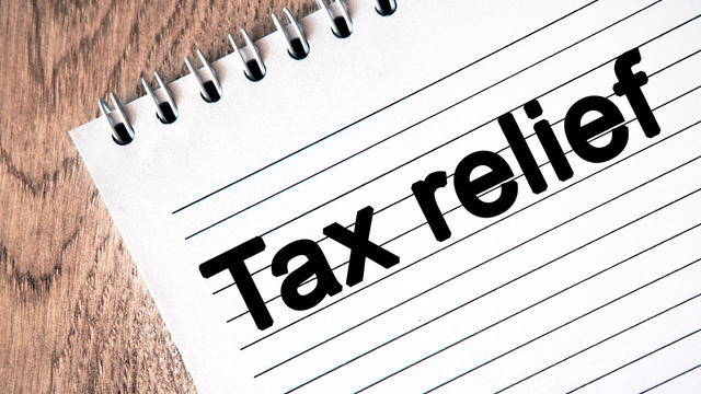 Text - tax relief on a notebook sheet. Wooden table 