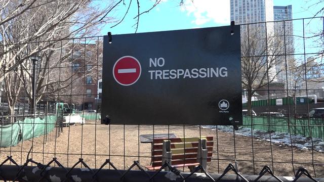 A "no trespassing" sign is posted on a fence outside a dog run at a park in Queens. 