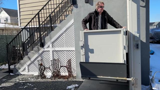 Matthew Doxsey stands in the elevator lift installed outside his Queens home. 