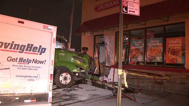 A tractor trailer sits directly outside a Popeyes in Brooklyn. The building has sustained damage to the exterior, as well as a door and window. 