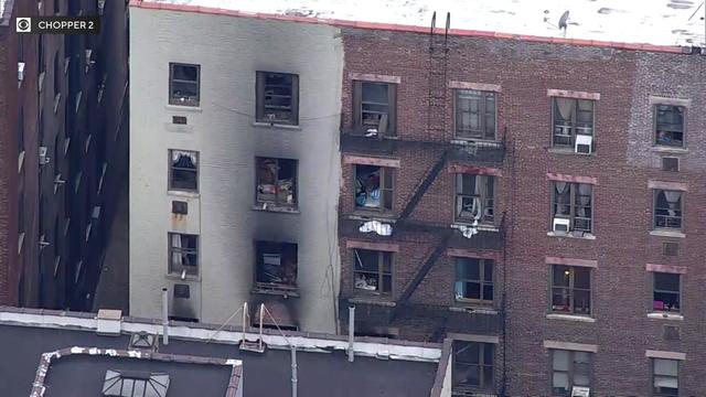 An aerial view of the exterior of a Harlem apartment building. Smoke damage can be seen surrounding windows. 