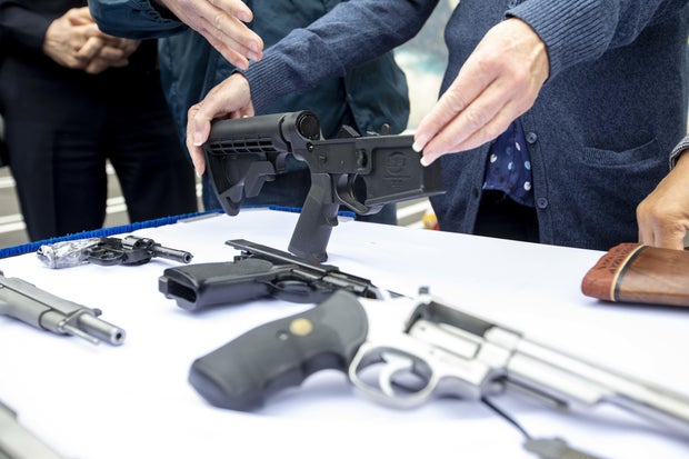 A bump stock and handguns collected during a buyback event in Los Angeles on Saturday, March 4, 2023.