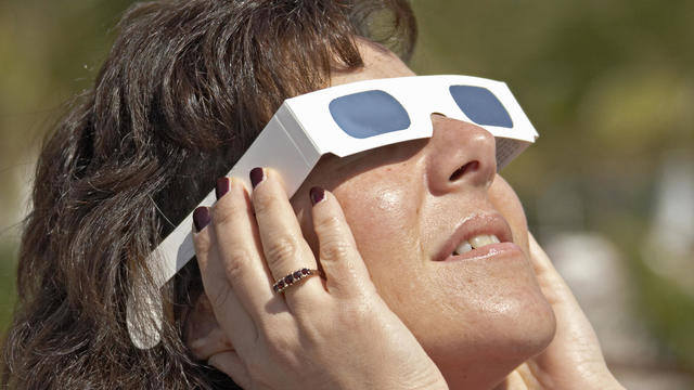 Woman with solar glasses looking at sun 