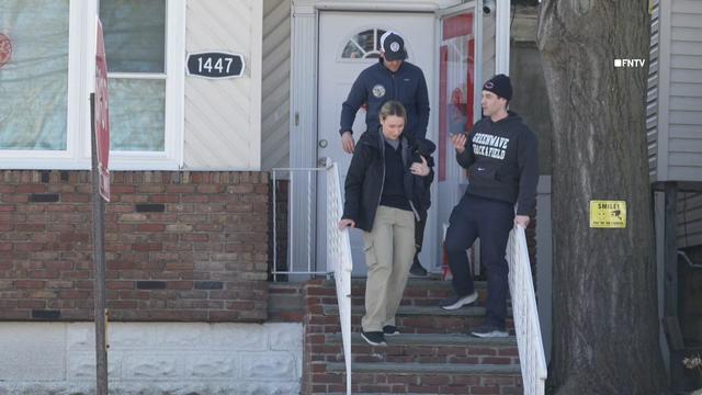 Three individuals walk down the front stairs outside a home in the Bronx. 