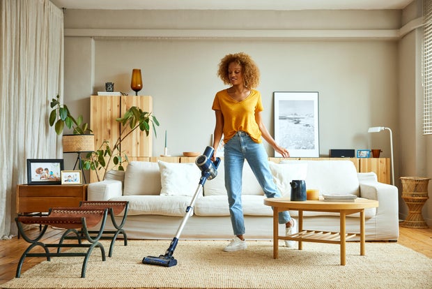Woman cleaning carpet with vacuum cleaner at home 