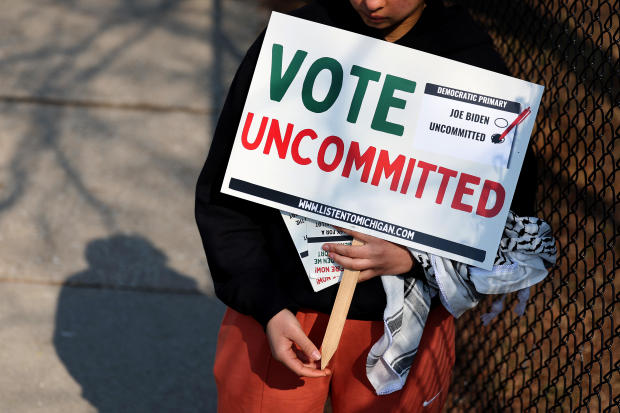 A voter holds a sign urging support for voting "uncommitted" against President Biden in the Democratic primary outside of a polling location on Feb.  27, 2024, in Dearborn, Michigan. 