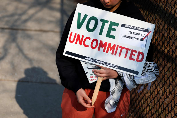 A voter holds a sign urging support for voting "uncommitted" against President Biden in the Democratic primary outside of a polling location on Feb. 27, 2024, in Dearborn, Michigan. 