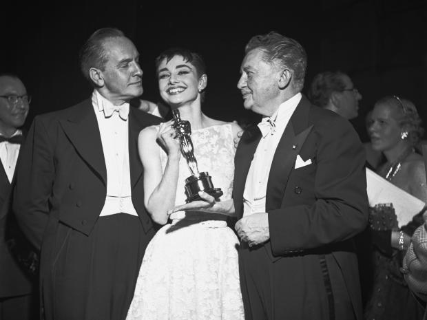 Audrey Hepburn smiles with her best actress award for her performance in "Roman Holiday" while standing between Oscars co-host Fredric March, left, and former academy President Jean Hersholt at the Academy Awards at the NBC Century Theatre in New York Cit 