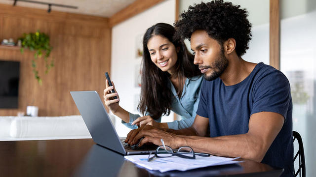 Couple at home paying bills online using a laptop, online taxes 