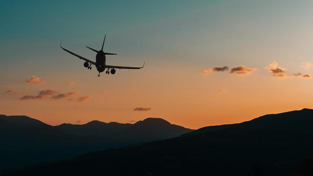 Silhouette of an airplane flying over the mountain range at night. Emergency landing at a remote location or a lost cargo plane 