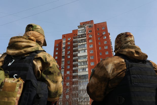 Self-defense unit volunteers are seen in front of a damaged high-rise apartment building following fresh aerial attacks in Belgorod, Russia, March 21, 2024