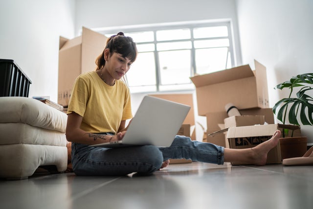 Young woman using laptop at new house 