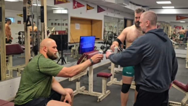 Jacon Kelce, Danny Cage and Lane Johnson toast with beers in a gym
