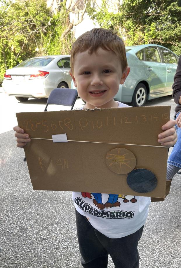 A little boy holds up a diagram showing the eclipse 