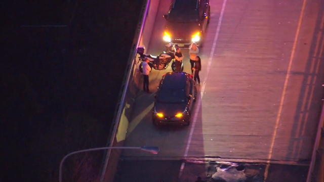 An aerial photo of a highway, police officers are standing near some cars and a bike 