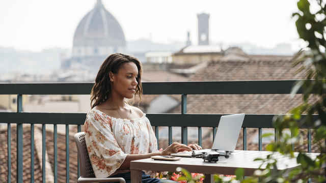 Young woman using laptop on a balcony in Florence, Italy 