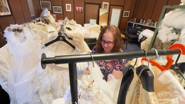 Fair Lawn Public Library director Adele Puccio looks through racks of wedding dresses in her office. 