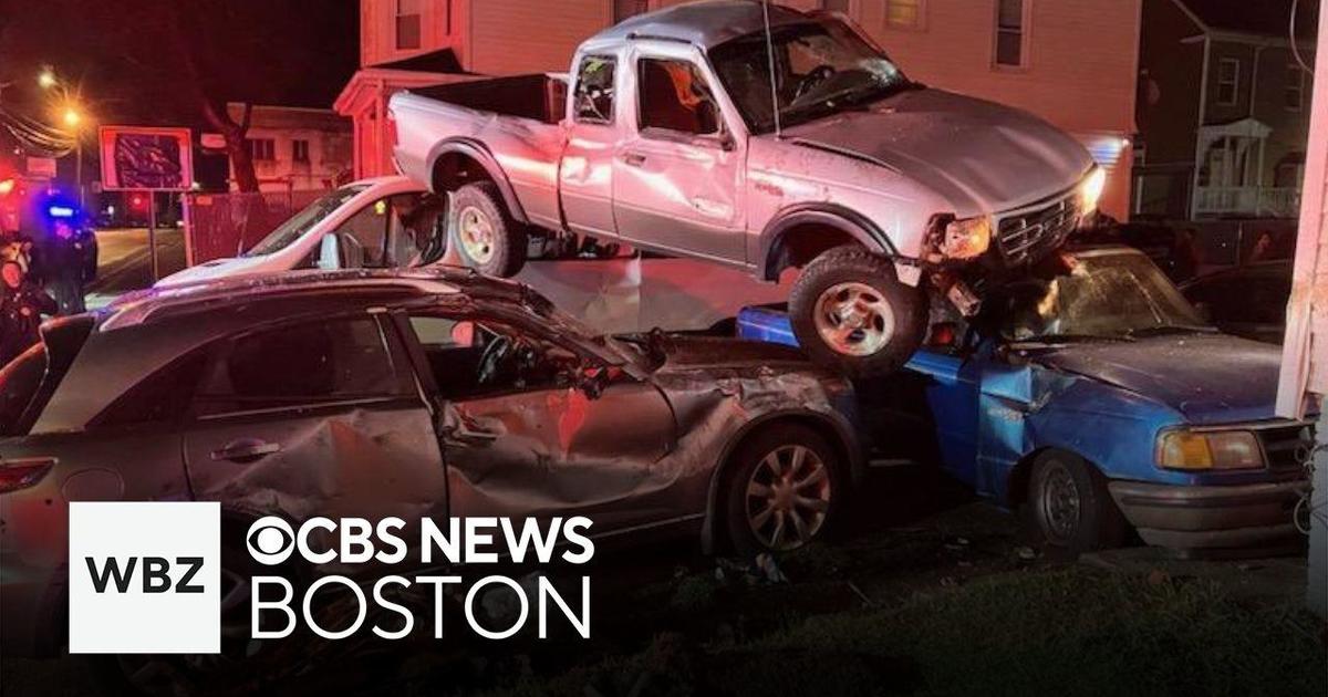 Driver flees crash after pickup truck lands on top of two parked cars in Brockton – CBS News