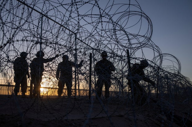 Soldiers repair razor wire laden fence after it was breached by migrants who entered El Paso, Texas