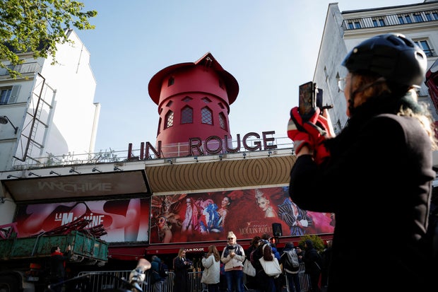 People take pictures of the landmark red windmill atop the Moulin Rouge, Paris' most famous cabaret club, after its sails fell off during the night in Paris