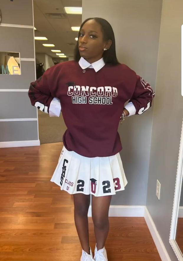 Camay Mitchell De Silva wearing a Concord High School sweatshirt and pleated skirt that says Class of 2023 