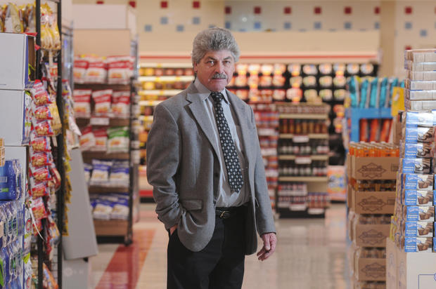 a man in a suit stands in the aisle of a grocery store 