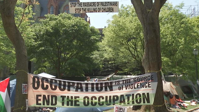 Banners hang near an encampment at the University of Pennsylvania. One says End the occupation. 