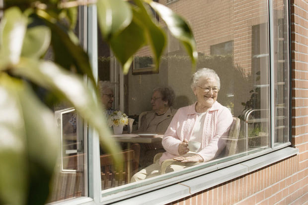Elderly women sitting in the window of a retirement home 