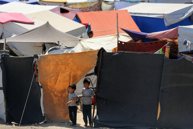 Displaced Palestinians sit outside to escape the searing heat in their camp tents in Deir El-Balah, in the central Gaza Strip, on April 28, 2024. 