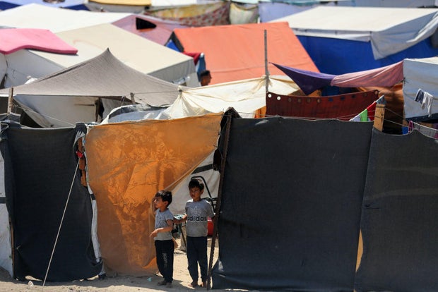 Displaced Palestinians sit outside to escape the searing heat in their camp tents in Deir El-Balah, in the central Gaza Strip, on April 28, 2024.