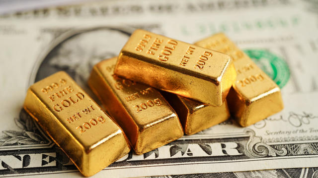 Gold bars on US dollar banknote money, finance trading investment business currency concept. 
