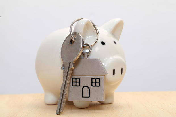 Piggy bank and house key against white background 