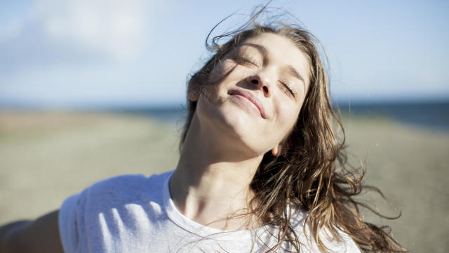 Young woman with eyes closed smiling on a beach 