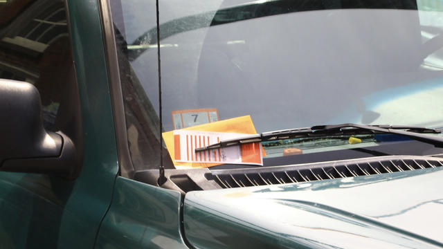 A parking ticket is seen on a car's windshield 