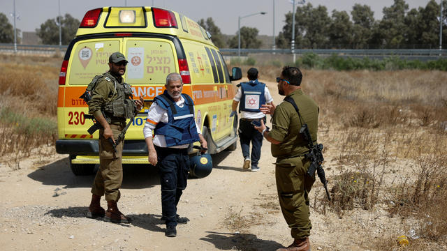 Israeli soldiers and medics walk near an ambulance after Palestinian Islamist group Hamas claimed responsibility for an attack on Kerem Shalom crossing 