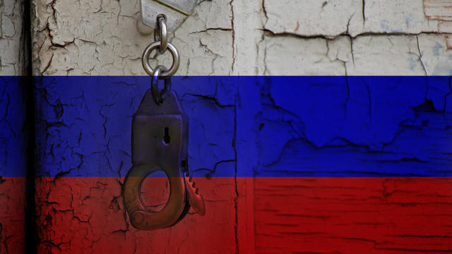 Handcuffs hang on an old cracked door against the background of the Russian flag, stop the war in Ukraine, Russia violates all laws, arrest 