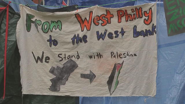 A sign hanging at the Penn encampment says "From West Philly to the West bank, we stand with Palestine" 