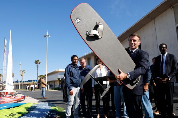 French President Emmanuel Macron holds a wingfoil board at the Marina Olympique nautical base in Marseille, France, on May 8, 2024, before the transfer of the Olympic flame to the shore of a 19th century sailing ship to mark the start of a journey of 7,500 miles torch passage through France and the country's most distant territories.