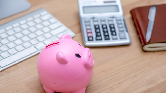 Savings and investment concept, pink piggy bank with calculator on pile or economic analysis report chart and graph on office table. 