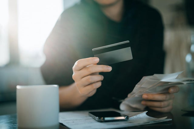 Cropped shot of young Asian woman holding credit card and expense receipts, handing personal banking and finance at home. Planning budget, calculating expenses and managing financial bills. Home budgeting. Home finances. Digital banking habits