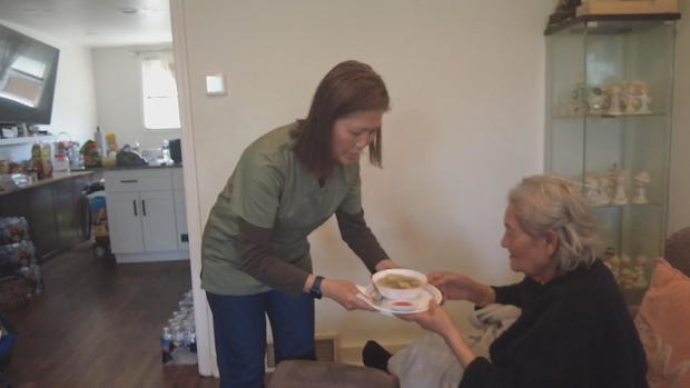 Phun Ing accepts a bowl of soup from her caregiver 