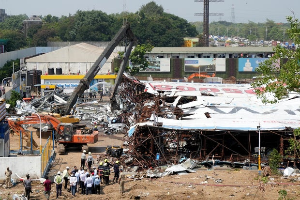 A machine is used to clear the debris at a fuel station after a massive billboard fell during a rainstorm in Mumbai