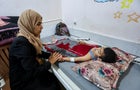 Palestinian boy Mohammed Imad, who was wounded in Israeli fire, is looked after by his mother as he lies on a bed at Al-Aqsa hospital in Deir Al-Balah in the central Gaza Strip 